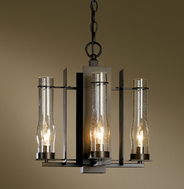 Hubbardton Forge New Town Wrought-Iron Chandelier hand-forged in Vermont, USA using the same techniques blacksmiths have used for centuries. The seeded glass hurricane shades are reminiscent of candle holders and oil lanterns before electricity. 