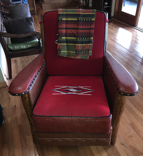 This looks like a Marc Taggart club chair with red wool Chimayo weavings on the cushions, leather and nail heads at the Auction Preview at Indian Cave Lodge